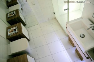 Biała łazienka z dużą ilością schowków , szafek i przestrzeni do przechowywania rzeczy (łącznie z koszem na pranie wmontowanym w szafkę koło WC) została zaprojektowana w duchu minimalizmu w kawalerce w centrum Warszawy. Do głównych założeń należało maksymalne wykorzystanie przestrzeni oraz uwzględnienie systemu nagłośnienia zsynchronizowanego ze sprzętem grającycym w salonie. 