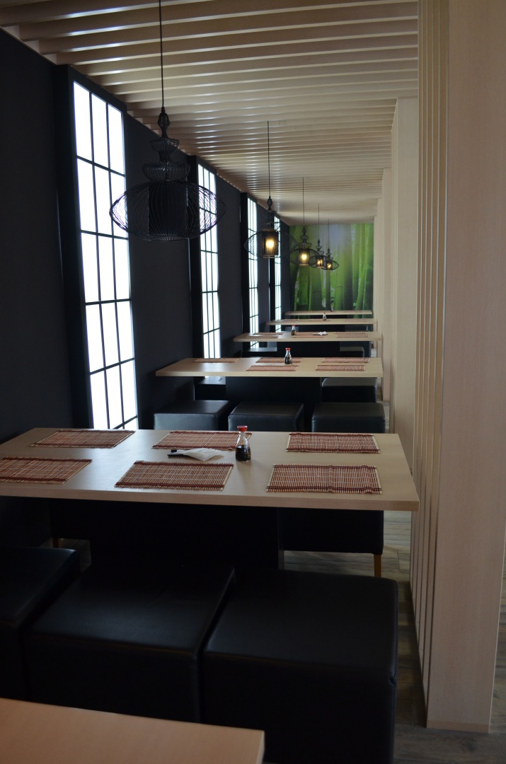 Świetlne japońskie kratownice, drewniane ścianki i sufit, proste tapicerowane siedziska i ażurowe lampy nad stolikami, to część sushi. Fot. Archimental