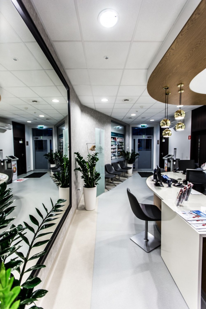 Odwiedzających klinikę wita przestronne lobby utrzymane w tonacji chłodnej bieli przełamanej ciepłym orzechowym drewnem wykorzystanym w wykończeniu lady recepcyjnej i jako element dekoracyjny na ścianie. Charakterystyczny detal stanowią wiszące nad recepcją złote lampy, przykuwające wzrok ciekawą formą. Fot. Forbis Group