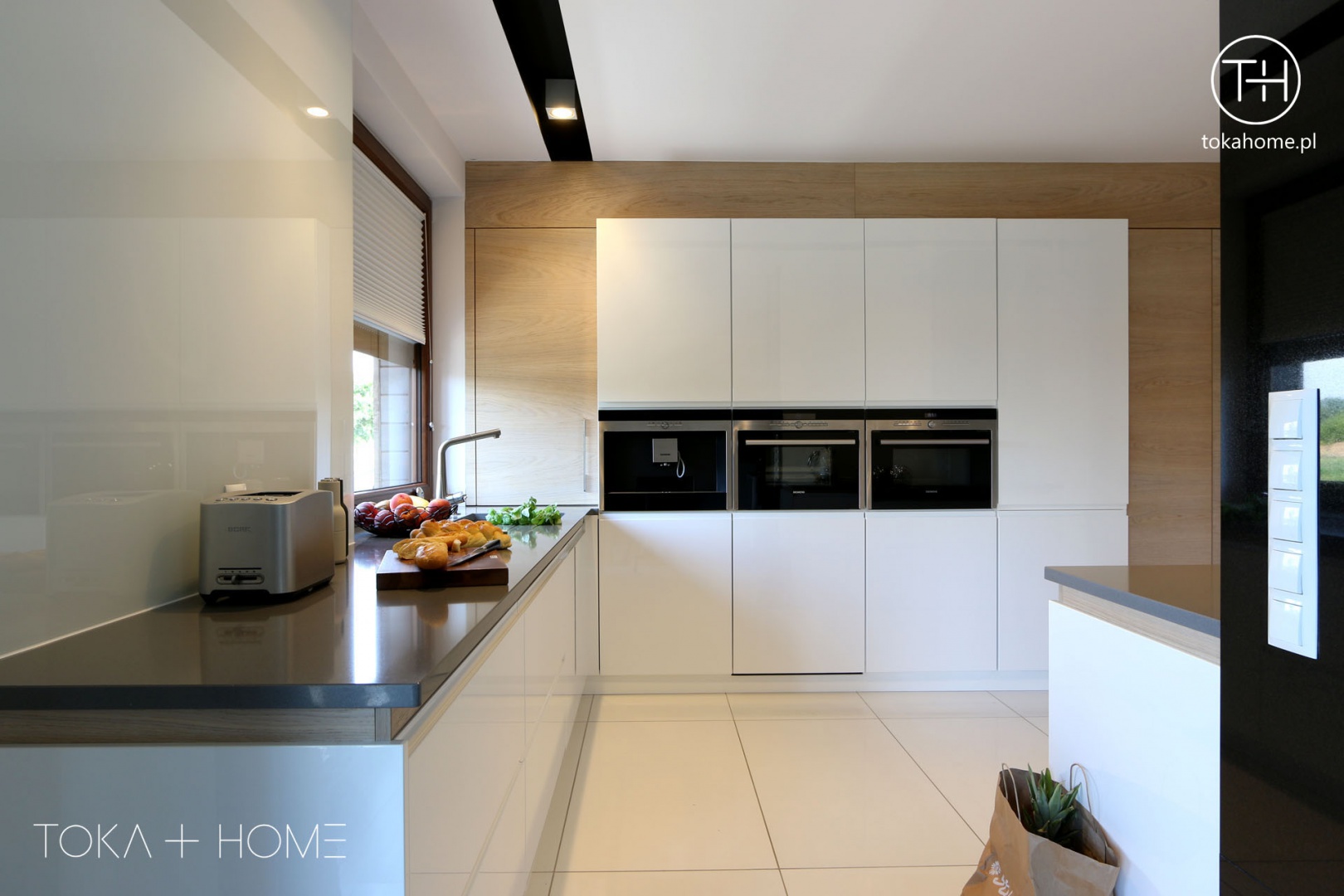 Biała kuchnia z drewnem zachwyca nowoczesnością i minimalizmem formy. Projekt TOKA + HOME. Fot. Archiconnect.jpg